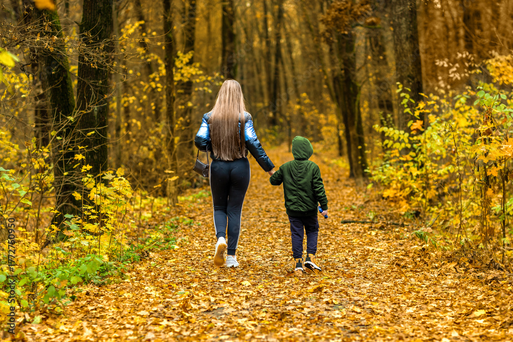 Fototapeta premium Mother and son walking in autumn forest