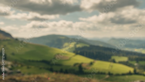 Blurred mountain landscape featuring fields and pathways, seasonal change