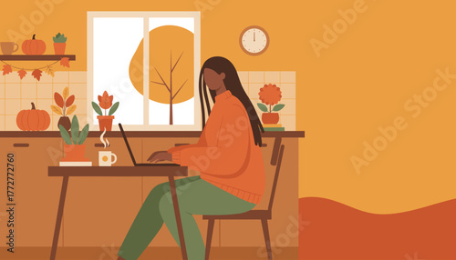 Woman works remotely on laptop in a cozy kitchen setting enjoying the autumn season