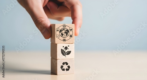 Hand stacking wooden blocks with eco friendly symbols for sustainability