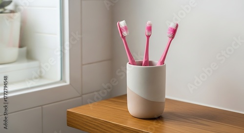 Three Pink Toothbrushes in a Cup on Wooden Shelf: Oral Hygiene