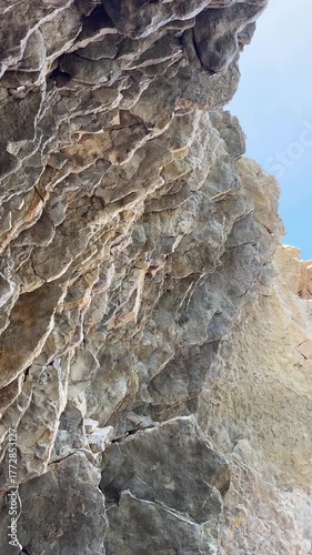 Rock formation with intricate textures, camera pans upward revealing sky