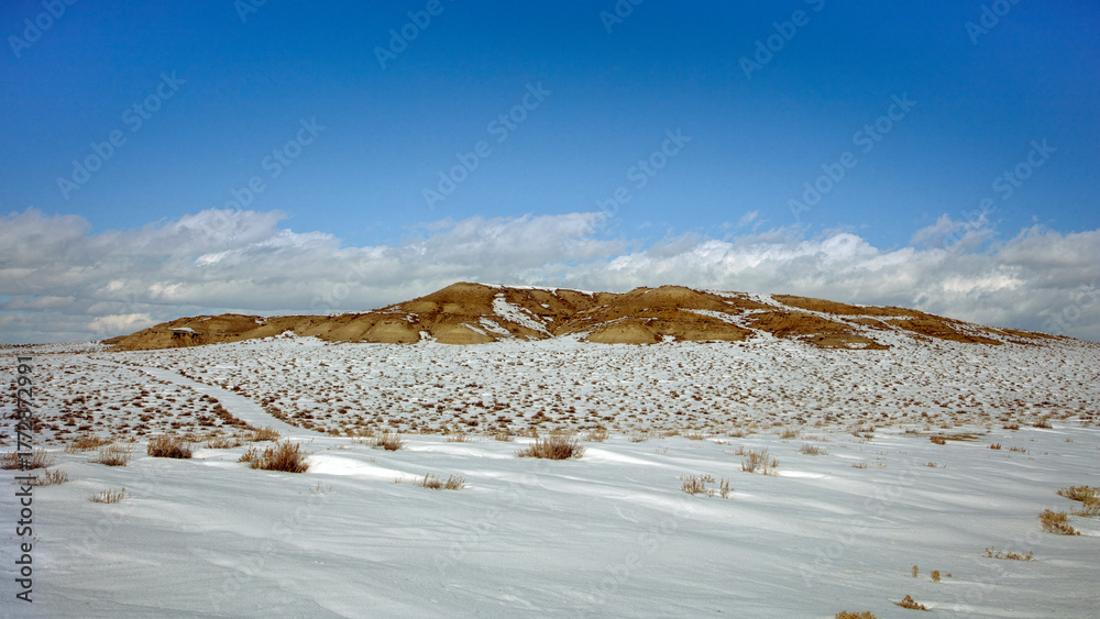 Obraz premium Snow-Covered High Desert Landscape with a Barren Mesa and a Winding Path