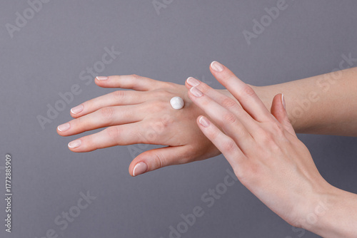 Woman applying moisturizing cream on hands, Close-up of female hands applying white moisturizing cream on skin, showing skincare, hydration, softness, and personal care routine.