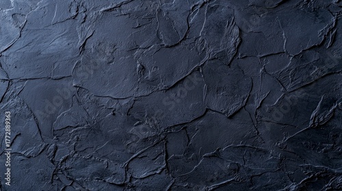 Textured dark stone surface with rough and smooth patches for artistic or design uses