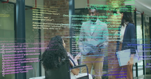 Collaborating team in blazers projecting code snippets in office hallway with laptop and wheelchair