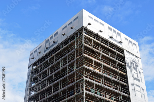 City Building Encased in Scaffolding seen from Below against Blue Sky