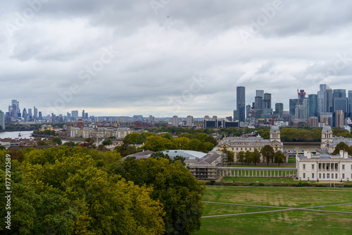 Фотография Greenwich Park view of London: classical buildings, River Thames, and the soaring Canary Wharf skyline under an overcast sky