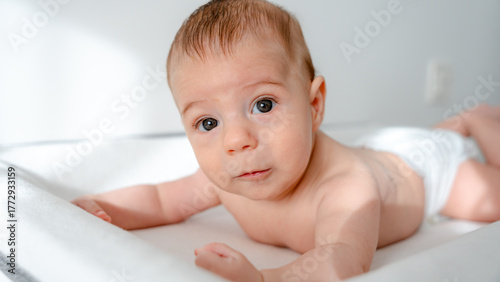 Baby in diapers lying on a white changing pad