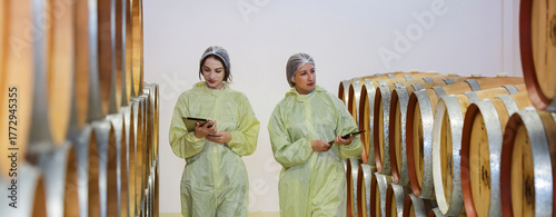 Winemaker working in modern large winery factory liquor drink industry quality. Staff inspecting wine in modern wine factory. Winery manufacturing quality control. Alcohol and wine winemaking process