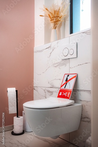 Private bathroom with funny warning sign on toilet