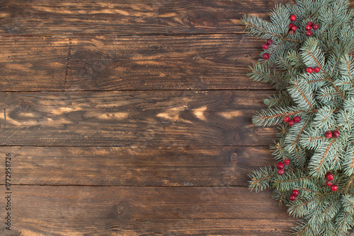 Christmas composition of fir branches and berries of viburnum on a wooden background . Top view with copy space.