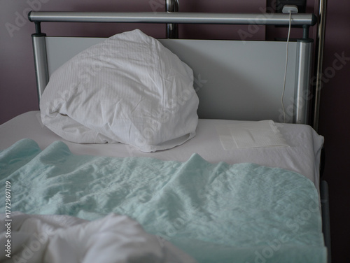 Comfortable hospital bed with white pillow and medical blanket in patient room, showing real healthcare environment and recovery space. High quality photo