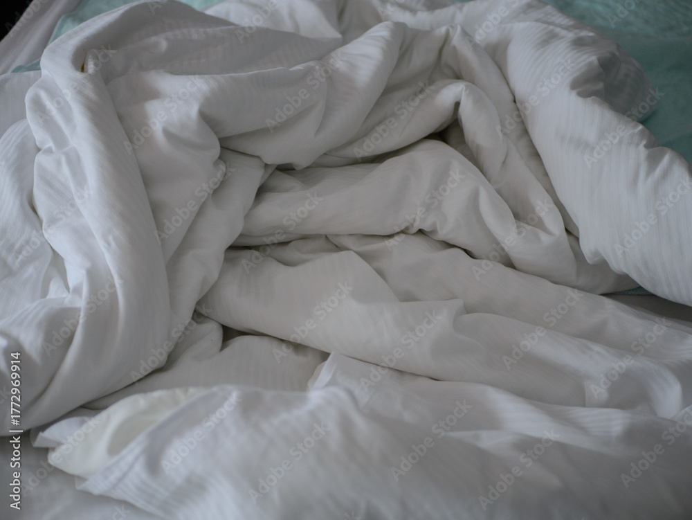 Obraz premium Unmade white hospital bed with crumpled bedding and soft natural light creating a calm clinical atmosphere in a healthcare patient recovery. High quality photo