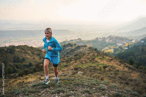 Woman jogging uphill on mountain trail during sunrise