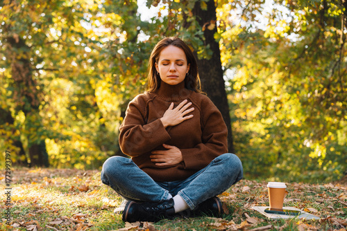 Obraz na plátně Woman in meditative pose outdoors in autumn tree area doing breathing exercise
