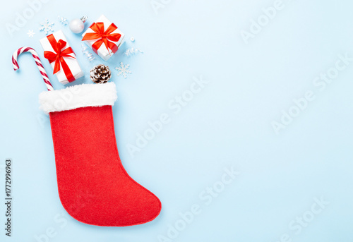 Christmas sock with gifts and decoration on color background, top view
