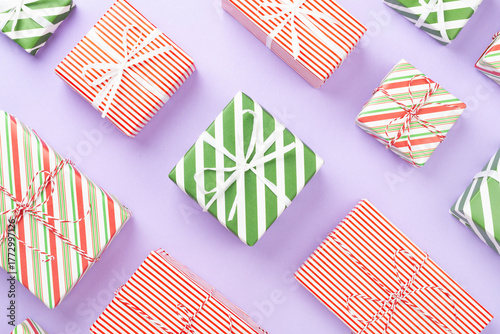 Many striped Christmas gift boxes on color background, top view
