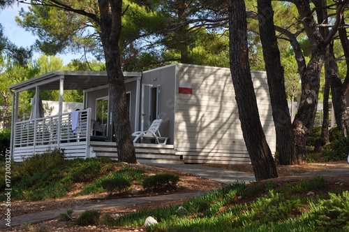 Modern modular square white architecture of a camping house with terrace exterior with flower garden and small path for tourism business