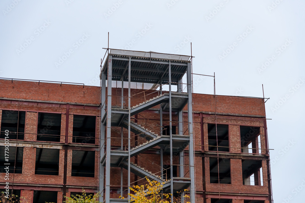 Obraz premium Construction progress of a modern building with steel staircase and brick walls