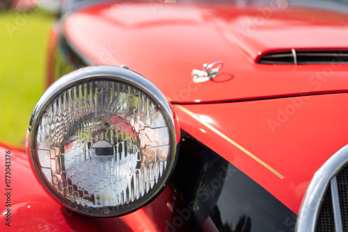 A vibrant close‑up of a red Morgan sports car, capturing the rich paint finish, chrome trim and vintage British roadster flair. The detailed shot emphasises the badge, bodywork curves and styling cues