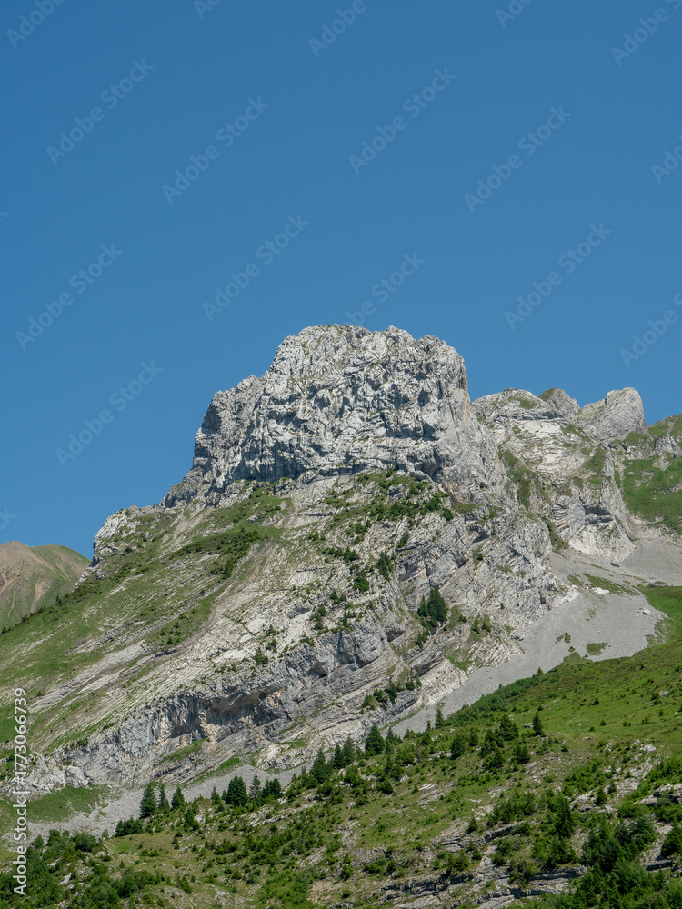 Fototapeta premium Impressive rock plateau and rugged mountain peak with lush green slopes.