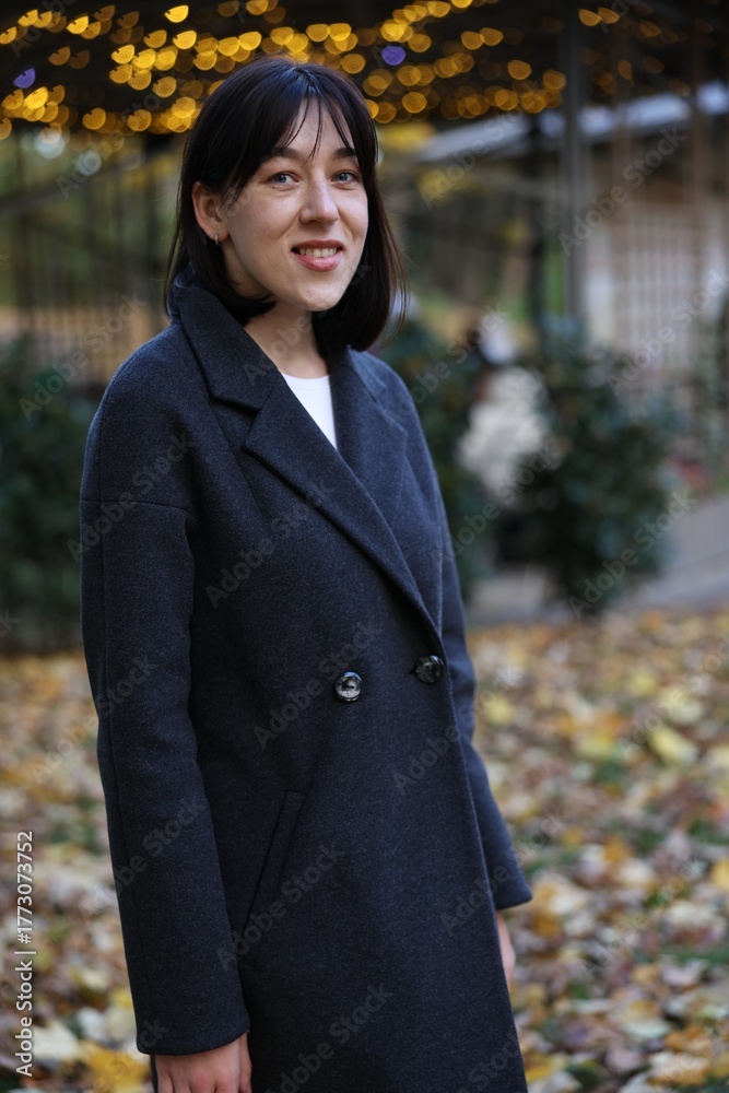 Fototapeta premium Smiling woman wearing coat in autumn park