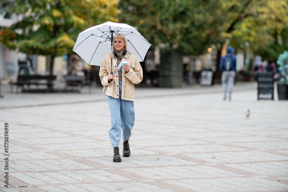 Obraz premium Woman walking city street with umbrella and coffee