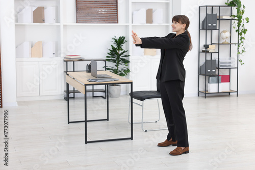 Wallpaper Mural Young businesswoman doing stretching exercise in office Torontodigital.ca