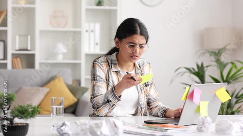 A tired young Indian girl gets angry from the number of tasks, crumples up the paper and throws it away, tries to calm down by meditating. Stressful work and study, overtasking.
