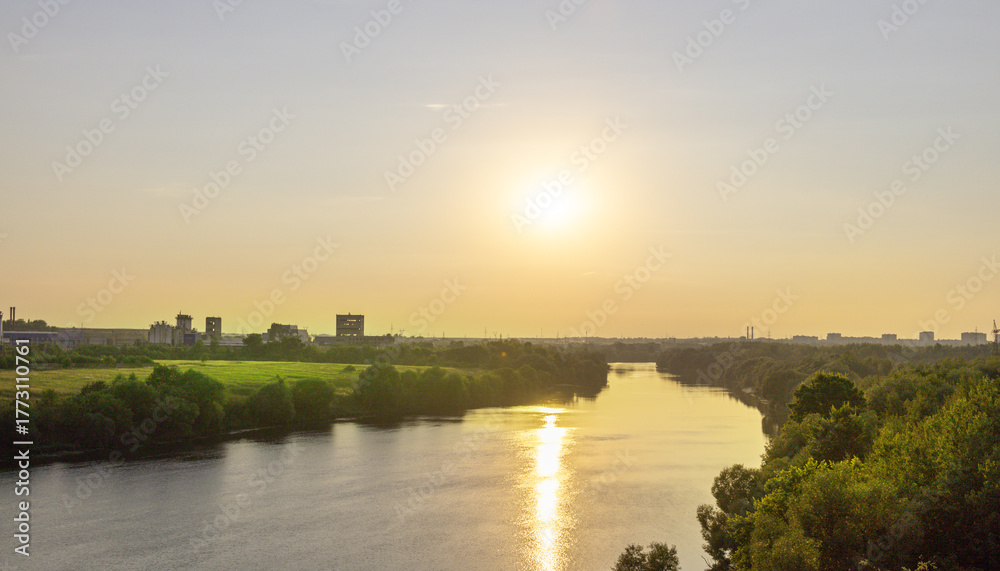 Obraz premium The sun is setting over a river, casting a warm glow on the water