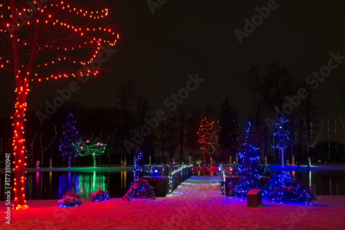 Colorful Christmas lighting adorns a viewing platform on a small lake and the trees around it in a northeast Ohio city park.