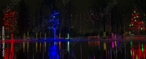 Christmas lights across a small lake reflect their colors in the still water in a northeast Ohio city park.