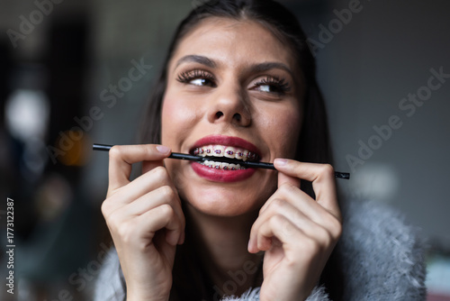 Smiling woman with dental braces holding a black straw, expressing happiness and confidence