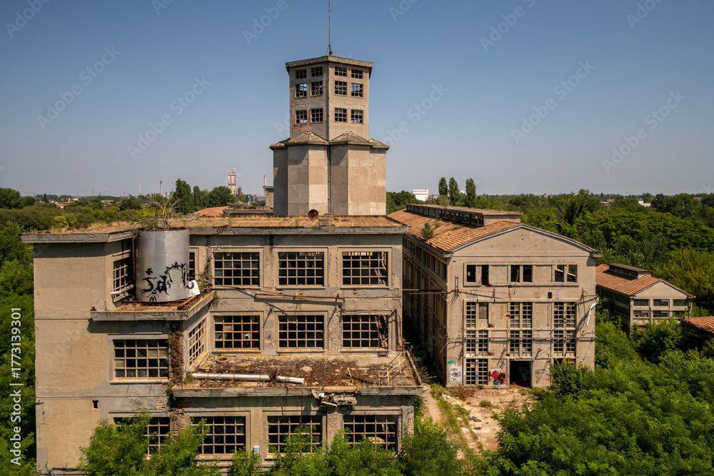 Fototapeta premium Abandoned distillery tower in Italy – circular industrial building with glass dome, steel beams, panoramic windows, decaying factory interior, urban exploration, post-industrial architecture
