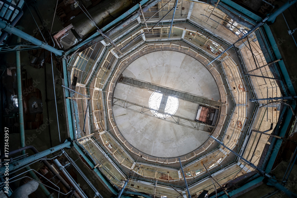 Obraz premium Abandoned distillery tower in Italy – circular industrial building with glass dome, steel beams, panoramic windows, decaying factory interior, urban exploration, post-industrial architecture