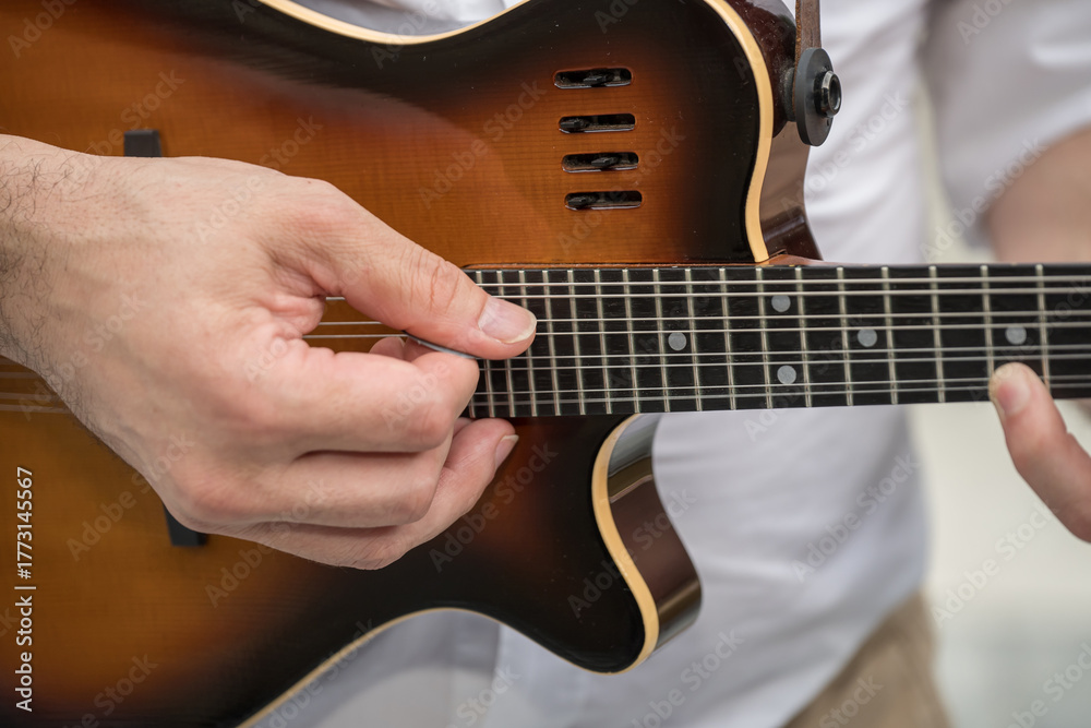 Fototapeta premium a person playing a Godin A8 electric mandolin. This is an 8-string mandolin,