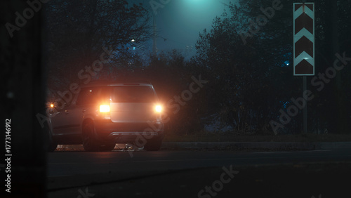A car with its hazard lights on on a city street at night