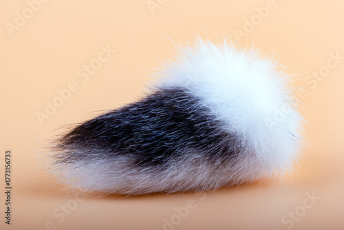 Black and white tail of a rabbit on a light peach background. Symbol of good luck. Protective amulet.