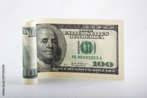 Rolled one hundred dollar bill on a white background. The concept of saving cash.
