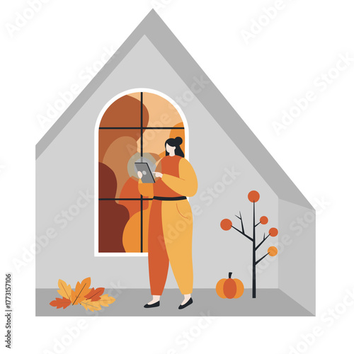Digital connection during fall Woman uses tablet indoors near cozy window with seasonal decor