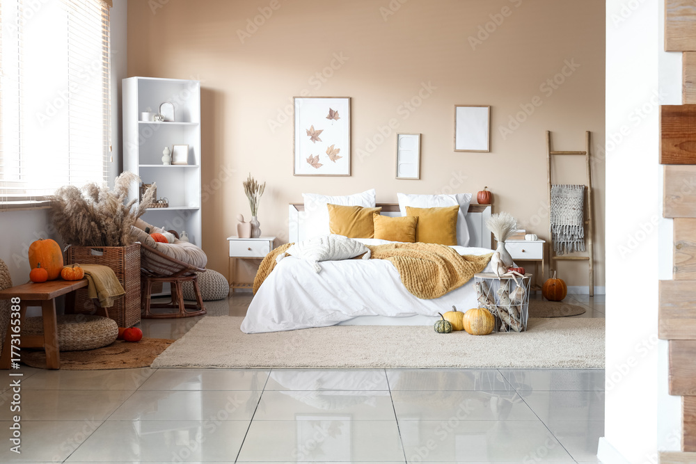 Obraz premium Interior of modern bedroom with comfortable bed, bench, shelving unit and pumpkins