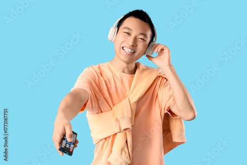 Young Asian man with TV rem...