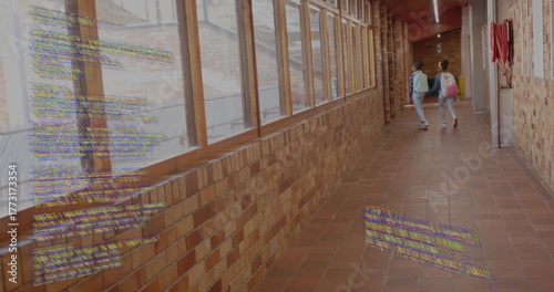Walking two schoolgirls carrying backpacks in school corridor, with fire extinguisher, copy space