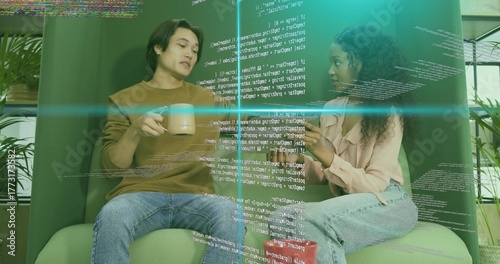 Coworkers discussing software code in break area, green chairs, coffee mugs and holographic overlay