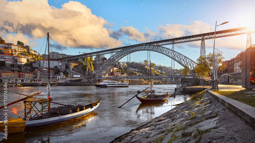 Naklejka premium Porto old town, Portugal. Evening sunset with sunshine. Panoramic view at Ponte de Dom Luis on Douro river. Traditional boats with port wine barrels.