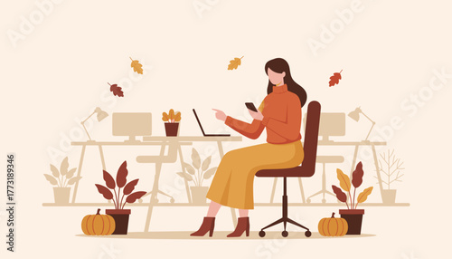 Woman uses laptop and smartphone for autumn remote work in a cozy decorated office