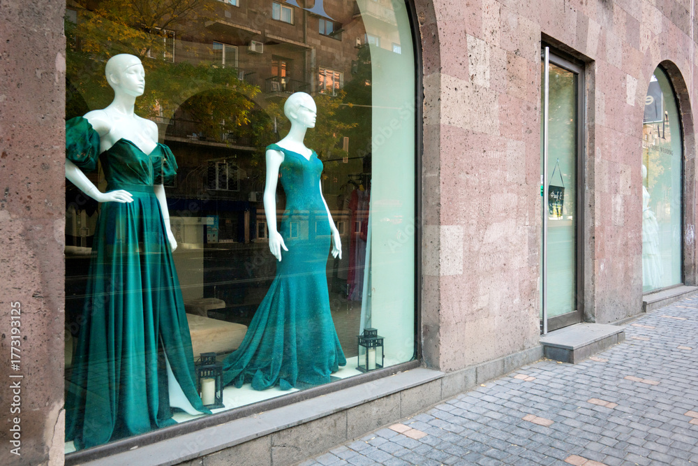Naklejka premium A window display of green gowns in a store