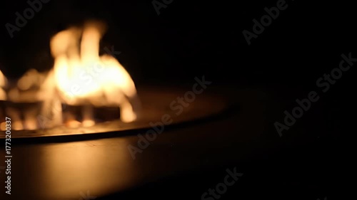 Soft focus close up of warm flames dancing in a modern fire pit at night.