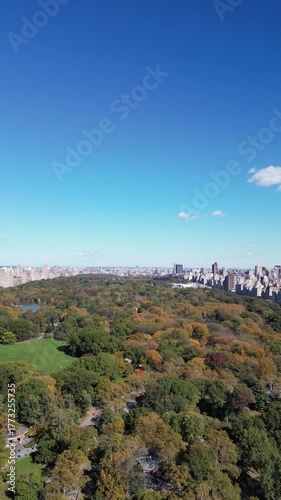 Aerial circling motion around Central Park capturing skyline and colorful foliage